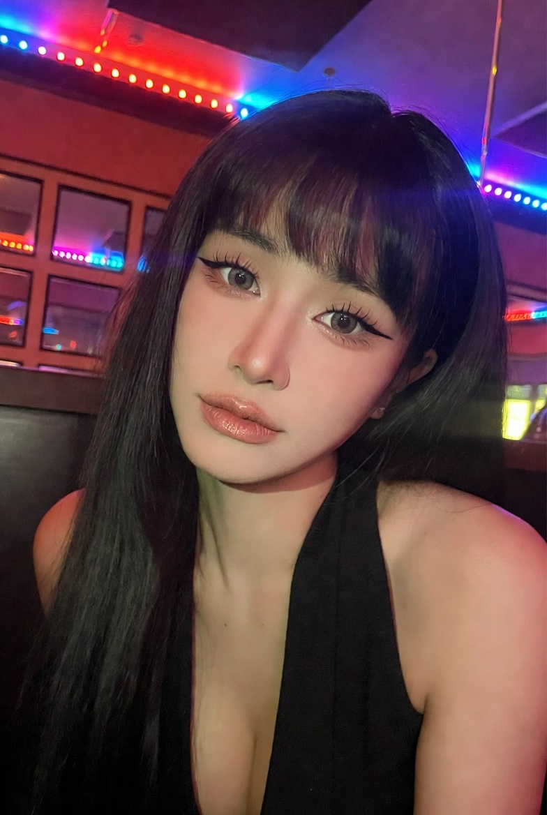 A low-quality iPhone photo of a Vietnamese idol in a karaoke room with colorful lights.