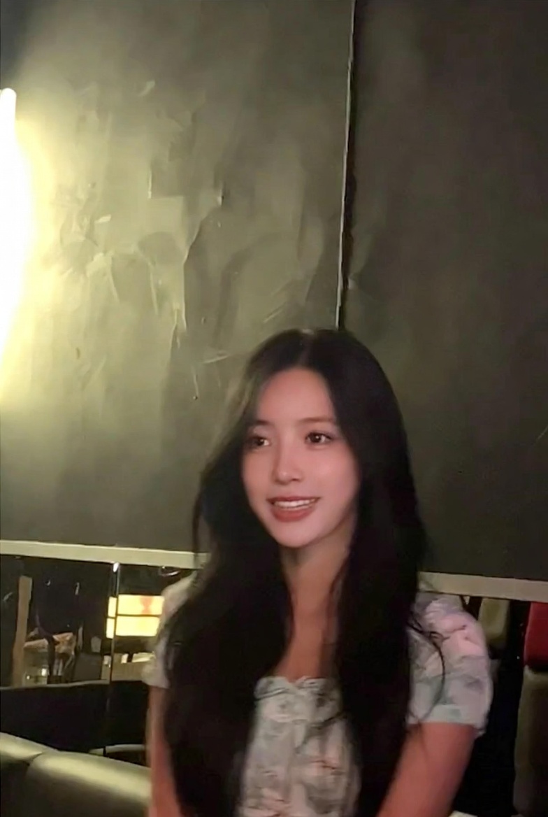 A low-quality iPhone photo of a Vietnamese idol singer in a karaoke setting, with dim lighting and warm glow.